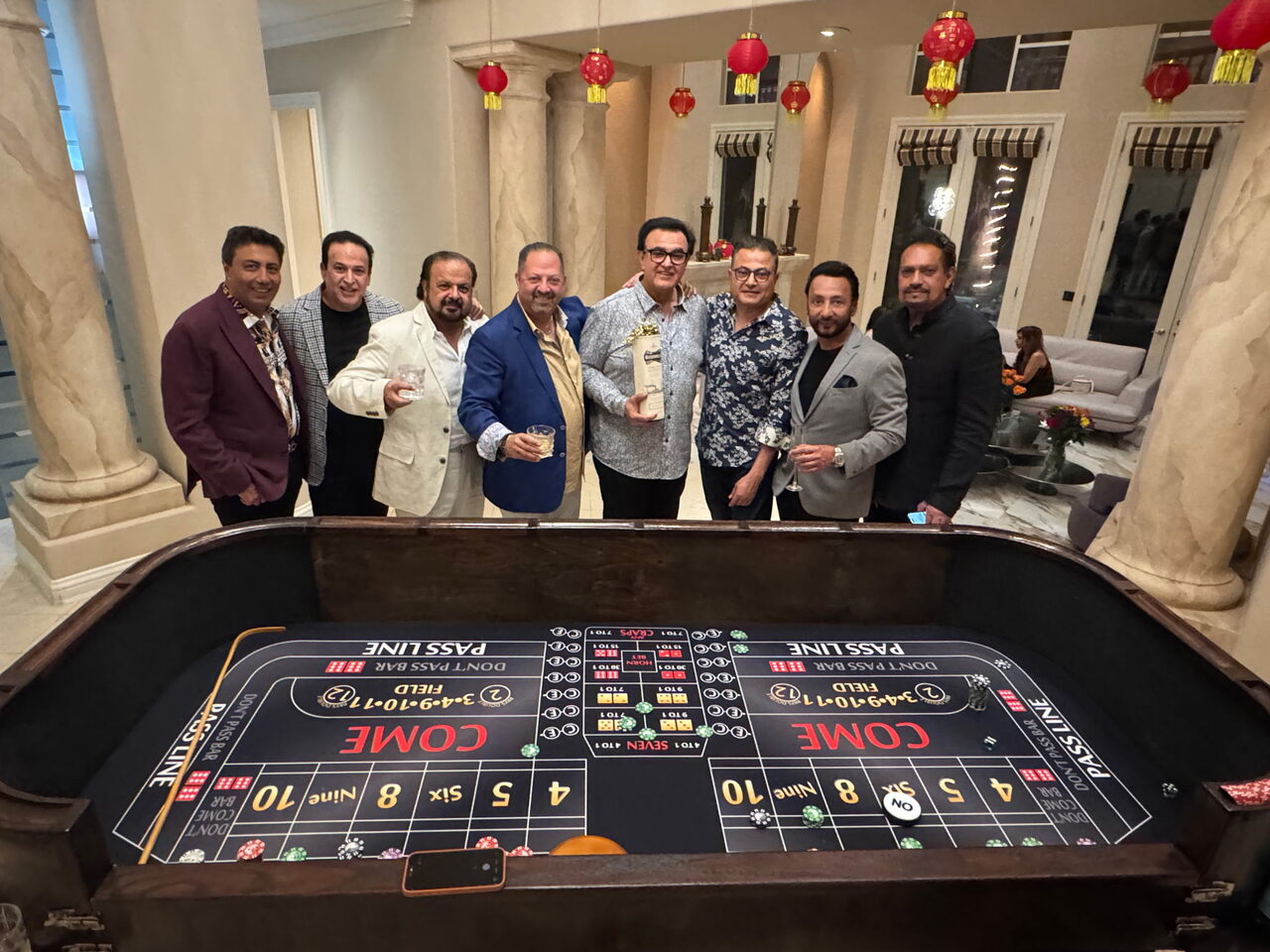 Friends celebrating around a craps table at a windward Oʻahu estate casino party