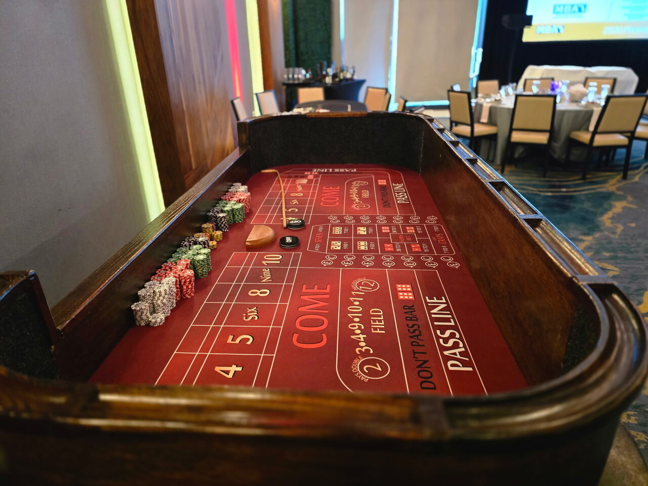 Red-felt craps table with a chip rail at a Honolulu corporate casino night