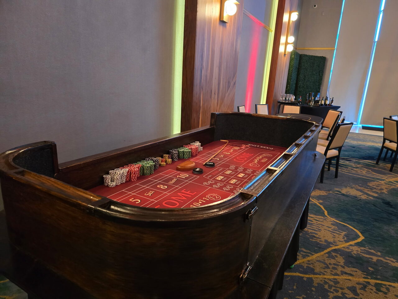Red-felt craps table in a modern neon-lit Honolulu event space